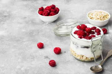 Glanola in glass jar with raspberry on a gray background. Copy space. Food background