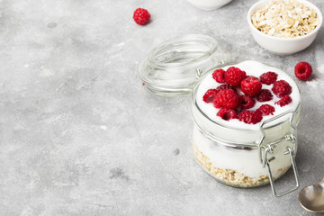 Glanola in glass jar with raspberry on a gray background. Copy space. Food background