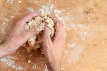 Man's hands making dough, preparing bread, pizza on brown wooden background with copy space....