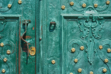 Old iron door, forged and painted in green color with golden flowers for background, vintage style, retro elements