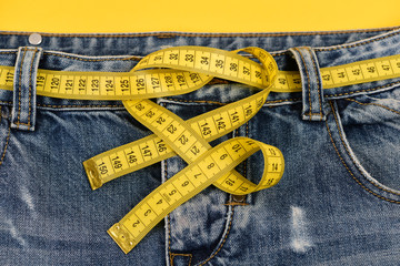 Top part of jeans with yellow measure tape as belt