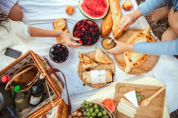 Foto op Plexiglas Picnic set with fruit, cheese, toast, honey, wine with a wicker basket and a blanket. Beautiful summer background with girl and products on nature © mikhail_kayl
