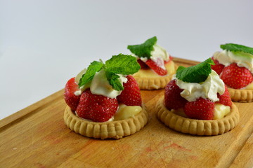 Small strawberry tarts on a wooden chopping board