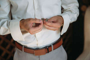 Groom hands with cufflinks. Elegant gentleman clother, white shirt and brown belt