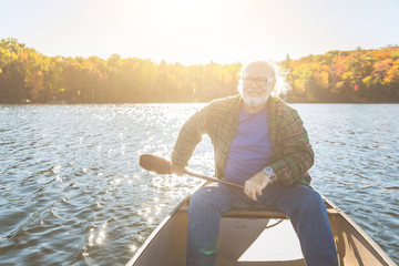 Senior man with canoe rowing on a sunny day