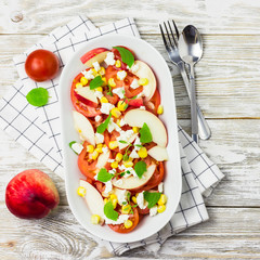 Summer salad with tomatoes, peaches,sweet corn, goat cheese and honey vinaigrette. Top view, copy space.