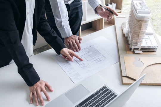 Engineering or Creative architect in construction project, Engineers hands working on construction blueprint and building model at a workplace in office, Building and architecture concept