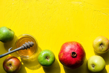 Apples with honey, pomegranate on a yellow table for the Jewish New Year