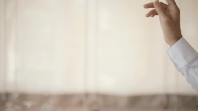The hands of the conductor of an orchestra directing the musicians with smooth movements. White background. Extreme close-up side shot.

