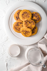Cup and jug with hemp milk, pumpkin pancakes on white table