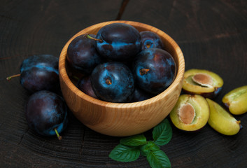 Bowl with  plums with green leaves