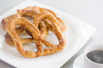 Pretzel bread white sesame in white dish and black coffee on gray background