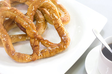 Pretzel bread white sesame in white dish and black coffee on gray background