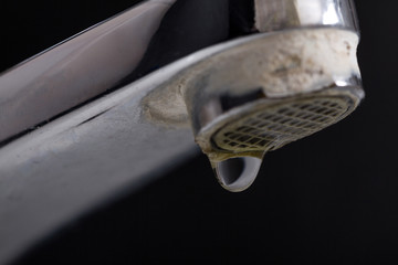 Old leaking faucet with stone and calcium sediments due to hard water.