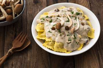 Plate of ravioli with cream sauce on wood table