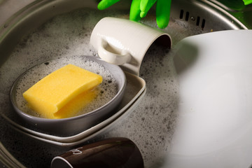 Sink full of washing dishes filled with dish soap water.