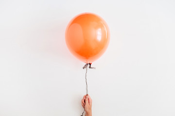 Halloween minimal concept. One orange balloon on white background. Flat lay, top view.