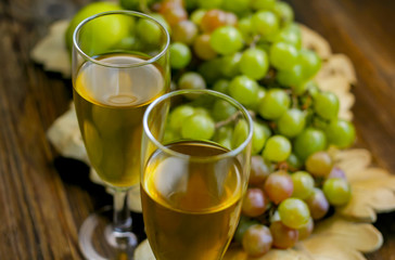 Two glasses and grapes in a decorative basket on a wooden surface.