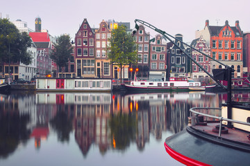 Amsterdam canal Amstel with typical dutch houses and houseboat from the boat in the morning, Holland, Netherlands.