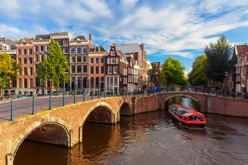 Foto auf Alu-Dibond Amsterdam canal Reguliersgracht with typical dutch houses, bridge and houseboats during sunny morning, Holland, Netherlands. © Kavalenkava