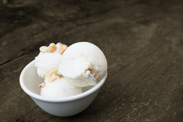Coconut ice cream in white bowl on old wood background