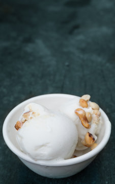 Coconut ice cream in white bowl on old wood background