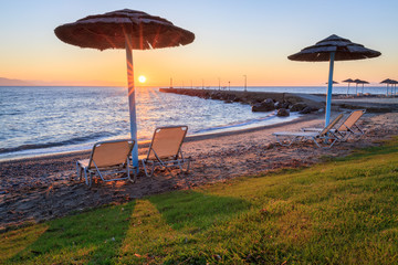 Beach umbrellas and sunbeds on pebbles beach.