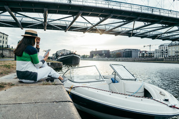 young pretty woman in hat sitting on pier in the morning