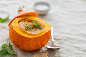 Creamy pumpkin soup puree in the whole squash on table ready to eat