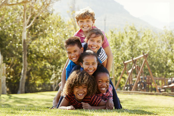 Pre-teen school friends lying a pile in a park