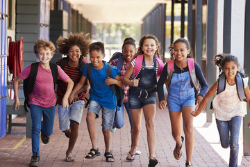 School kids running in elementary school hallway, front view