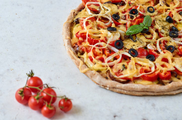 Fresh baked hot pizza on white background with copy space on the left side. Vegetarian pizza with vegetables and basil. Decorated with branch of cherry tomatoes. Side view