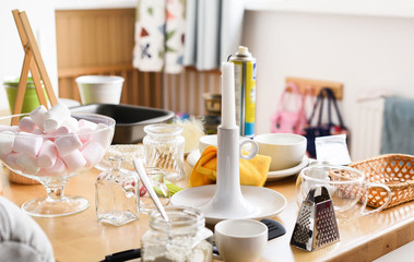 Marshmellow in glass vase, candle, grater and miscellanious kitchen utencils on wooden table