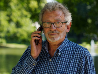 Aktiver Rentner im Park telefoniert mit Smartphone