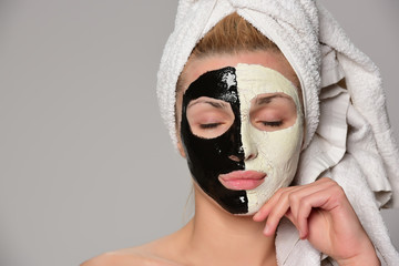 beautiful female model with black and white facial cosmetic mask posing. Isolated on gray background.