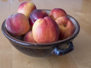 Glazed handicraft bowl full of colorful nectarines and peaches