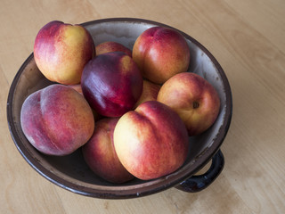 Fototapeta na wymiar Handicrafted bowl full of colorful nectarines and peaches