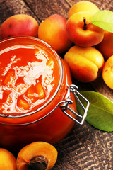 Jam from apricots in a glass jar on a wooden surface