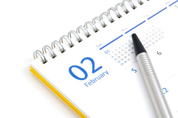 Desk calendar and pen on white background