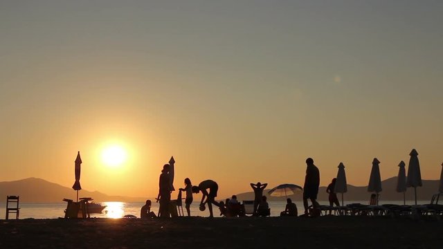 Silhouette of group of friends, young people, until they are playing volley on the beach.
