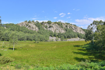 Panorama di una montagna collinare, con prato verde e cielo blu 