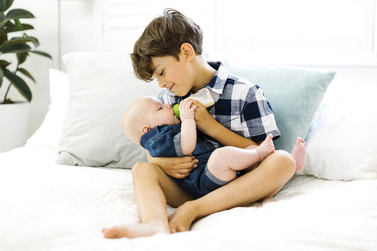 Young boy feeding baby brother