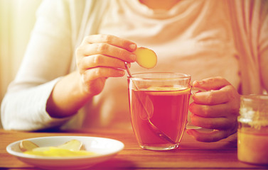 close up of woman adding ginger to tea with lemon