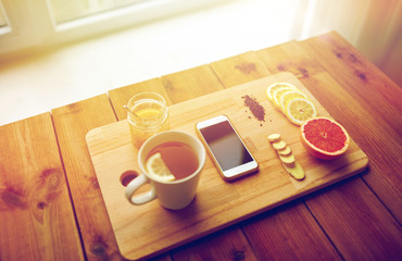 smartphone with cup of lemon tea, honey and ginger