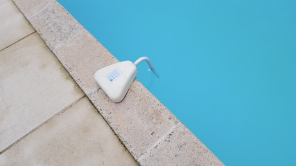Swimming pool alarm positioned on the side of a home private family pool
