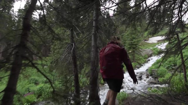 Hiking Colorado Girl Backpacker looks at cascading creek near lake Isabelle