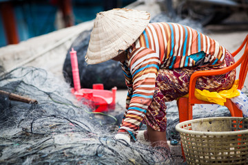 vietnamese woman repairing fishing net
