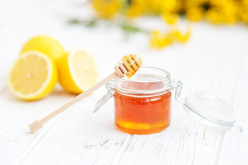 Honey in a glass jar and a lemon. Honey dipper. The concept of healthy food, vegetarianism, autumn, colds,  treatment, cure, therapy, medication.