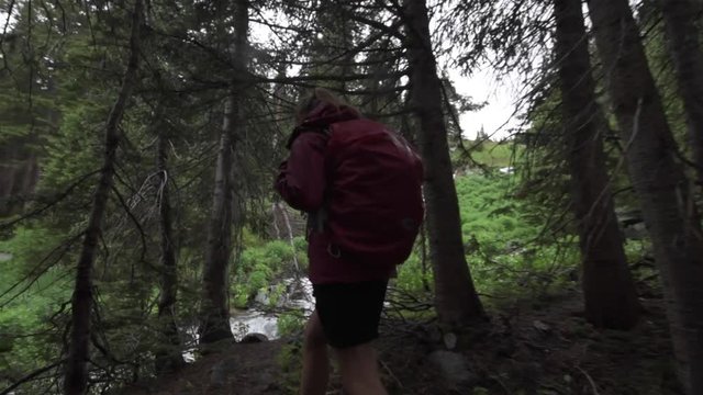 Hiking Colorado Girl Backpacker looks at cascading creek near lake Isabelle