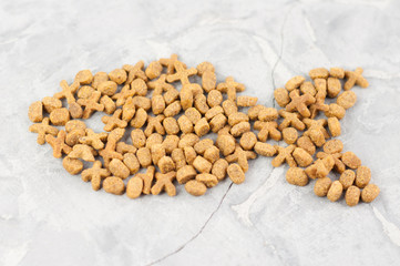 Fish laid out of dry brown cat food on old gray concrete floor